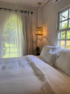 a bedroom with a white bed with a window at Hospedaria do Feno in Brotas