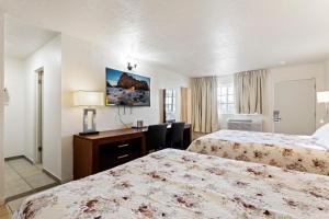 een hotelkamer met twee bedden en een bureau bij Temple View Inn in Ogden +3 foto's