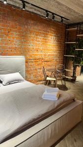 een bed in een kamer met een bakstenen muur bij Люкс в стиле LOFT in Pavlodar