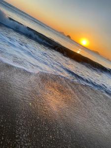 a sunset on a beach with the ocean at POUSADA MAORI Boiçucanga in Boicucanga