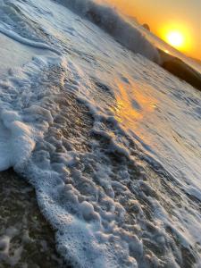 a beach with snow on the shore with the sunset at POUSADA MAORI Boiçucanga in Boicucanga