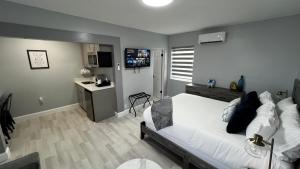 a bedroom with a white bed and a kitchen at Oceano Suites Daytona Beach in Daytona Beach