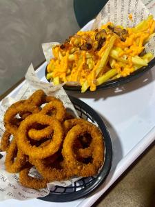 dos platos de aros de cebolla y papas fritas en una bandeja en POUSADA MAORI Boiçucanga en Boicucanga