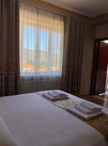British Hotel Pogradec في بورغراديك: غرفة نوم بسرير كبير عليها مناشف