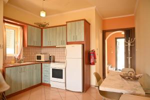 een keuken met een witte koelkast en een tafel bij liocharis villas in Lourdhata
