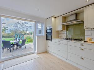 a kitchen with white cabinets and a table with chairs at 2 Bed in Isle of Purbeck DC118 in Arne