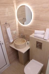 a bathroom with a sink and a mirror and a toilet at Gjinaj Apartments in Ulcinj