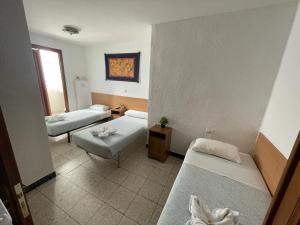 Cette petite chambre comprend deux lits et une table. dans l'établissement Pensión Fortea, à Saragosse