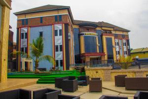 a large building with chairs in front of it at Emperor Melanie Hotels in Akwa