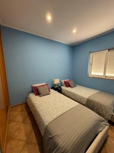 a bedroom with two beds and a blue wall at 21 on Pescadores T2 in Carvoeiro