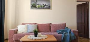 ein Wohnzimmer mit einem rosa Sofa und einem Tisch in der Unterkunft Best Two Room Apartment in Mukatschewo