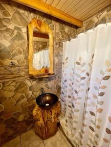 baño con lavabo en un tronco y espejo en Cabañas La Calchona, en Melocotón