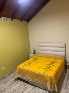 ein Schlafzimmer mit einem Bett mit gelber Decke in der Unterkunft LOS CLAVELES in Federación