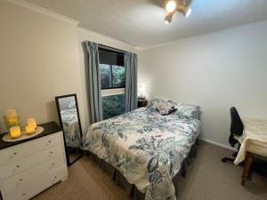 a bedroom with a bed with a dresser and a window at Waverley Comfort in Dunedin