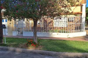 uma árvore com flores vermelhas na frente de uma cerca em Patuli House - Casa alquiler temporario Córdoba em Córdoba