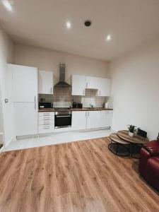 a kitchen with white cabinets and a wooden floor at CentralGem Retreat 01 in Redditch