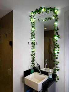 a bathroom with a sink and a mirror with plants at Studio Aconchego 115. Novo Ed. On Imarés - Moema. in Sao Paulo