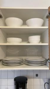 a shelf filled with white plates and bowls at Fewo Reutlingen Heinestrasse in Reutlingen +13 photos