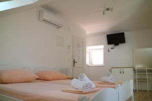 a white bedroom with two beds with towels on them at Studio Apartments & Rooms Lela in Šipanska Luka