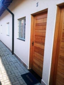 une maison avec une porte en bois sur le côté dans l'établissement Casa de cond com piscina e churrasqueira particular, à Itanhaém