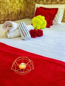 a bed with a red blanket and a candle on it at Pousada Vila do Sossego in Morro de São Paulo