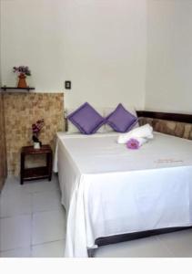 een slaapkamer met een wit bed met paarse kussens bij Pousada Vila do Sossego in Morro de São Paulo