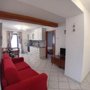 een woonkamer met een rode bank en een keuken bij Maison Clair Vda Gressan n 0094 in Aosta