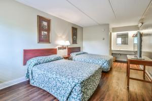 Cette chambre comprend deux lits et un bureau. dans l'établissement Economy Hotel Glenwood, à Decatur