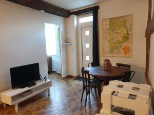 a living room with a table and a television at Appartement au cœur du Berry in Lignières