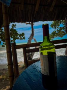 una bottiglia di vino seduta su un tavolo vicino all'oceano di Los Achiotes Hostal a Palomino