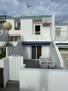 Casa blanca con balcón con mesa y sillas en Isis House en Maspalomas