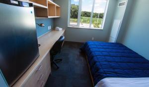 a bedroom with a bed and a desk and a window at Lakehead University Residence and Conference Centre in Orillia