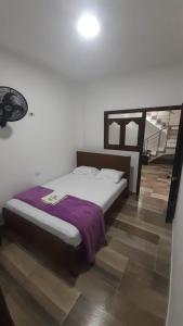 a bedroom with a bed with a purple blanket at Hotel Torrado in Ocaña