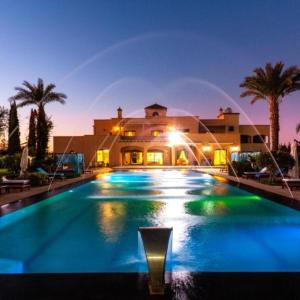 a large swimming pool in front of a house at Palais les sources de l'atlas & spa in Marrakesh