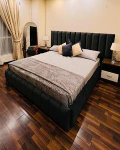 een groot bed met een zwart hoofdeinde in een slaapkamer bij LMY Elysium Designer Luxury Apartments Facing Centaurs Mall Islamabad in Islamabad