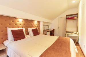 um quarto com uma grande cama branca com almofadas vermelhas em Pousada VHL - Campos do Jordão em Campos do Jordão