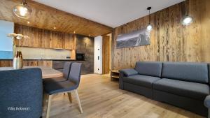 sala de estar con paredes de madera, mesa y sillas en Villa Dolomiti en Ortisei