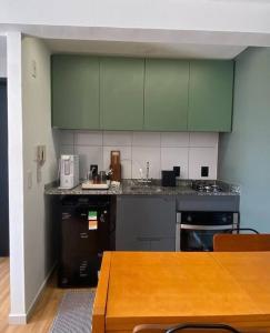 cocina con armarios verdes y mesa de madera en Apartamento Piauhy - Studio, en Teresina