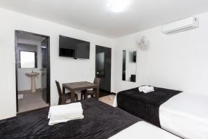 1 dormitorio con 2 camas y mesa con escritorio en Hotel De León Estadio, en Medellín