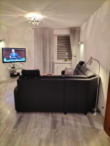 uma sala de estar com um sofá preto e uma televisão de ecrã plano em Apartament Ustroń Jaszowiec em Ustroń