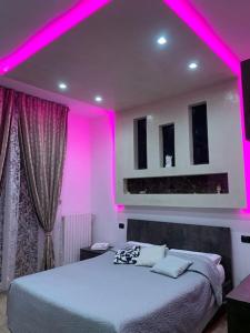 a bedroom with a bed with pink lighting at Appartamento Luxury Adri in Talignano