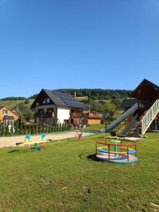 un parque infantil con toboganes y equipo de juegos en un campo en Gościnna Chata Domek, en Jaworki