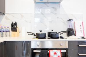 a kitchen with a stove with two pots on it at Brand New Modern Block of Apartments By AV Stays Short Lets London in Croydon