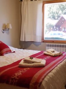 two towels on a bed in a bedroom with a window at Departamento Frente al Lago-San Martin de Los Andes in San Martín de los Andes