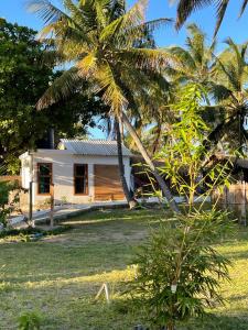 una pequeña casa blanca con una palmera en CosyBe Villas, en Inhambane