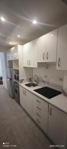 una cocina con armarios blancos y electrodomésticos de acero inoxidable en Andlous inn en Hurghada