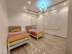 Habitación con 2 camas, paredes blancas y lámpara de araña. en Andlous inn en Hurghada