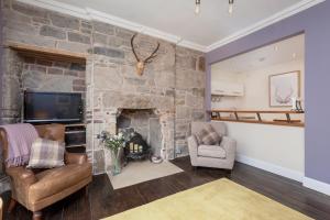 sala de estar con chimenea de piedra y 2 sillas en Rose Apartment, en Edimburgo