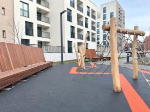 a playground with wooden benches in front of a building at Wygodne Mieszkania Nova Mikołowska 123 in Katowice