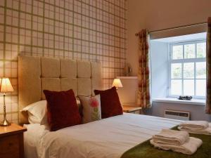 Un dormitorio con una cama con almohadas rojas y una ventana en Home Farm Cottages, Glendaruel, Argyll. Scotland en Clachan of Glendaruel